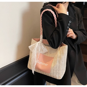 Detail of woven straw tote bag with pink leather handle, lace bow, and Summer patch