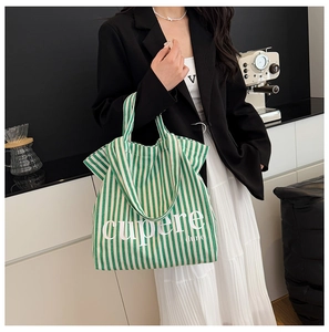 Detail of green and white striped canvas tote bag with white lettering held by a model