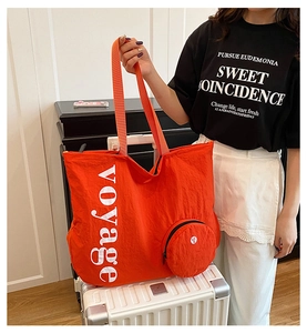 Détail du sac cabas en nylon orange avec imprimé voyage et petite pochette zippée sur valise
