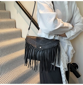 Close-up of black fringe crossbody bag featuring a V-shaped flap and metallic buckle