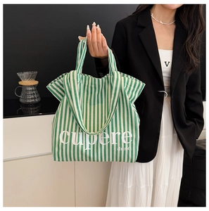 Detail view of large green striped canvas tote bag with Cupere print and handles