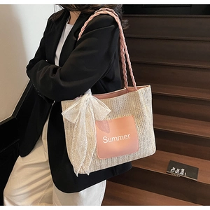 Detail of woven straw tote bag with pink leather Summer patch and white lace bow
