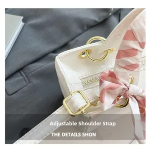 Gros plan du sac à main blanc à texture écailles avec bandoulière réglable et boucle dorée
