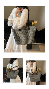 Detail of woven straw tote bag with black and white chevron pattern and leather straps