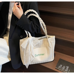 Close-up of woven straw tote bag with white lace bow and Summer patch detail