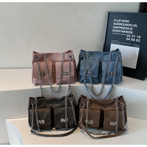 Détail de quatre sacs fourre-tout colorés en daim avec poches avant et chaînes argent