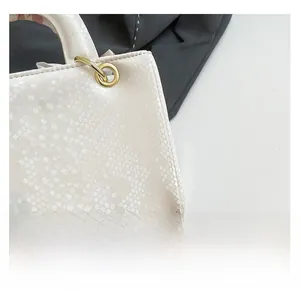 Gros plan d'un sac à main blanc à texture écaille avec détail d'anneau doré chic