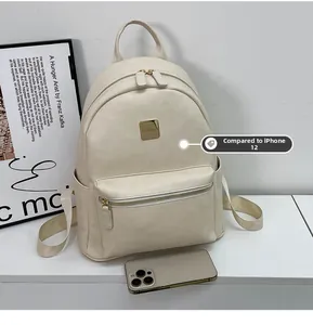 Detail view of cream faux leather backpack with gold metal plaque and phone size comparison