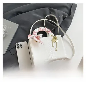 Détail du sac à main blanc à texture serpent avec foulard en soie et breloques dorées