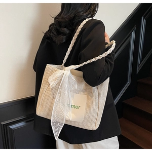 Detail showing woven straw texture with white lace bow and Summer print on tote bag