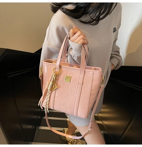 Detail of pink embossed tote bag with cartoon patterns and woven tassel accessory