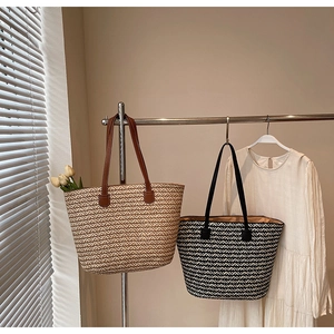 Detail showing handwoven straw tote bags with herringbone pattern and leather straps