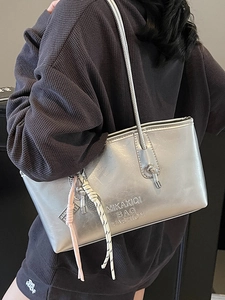 Silver metallic bucket bag with embossed lettering and decorative charm on shoulder