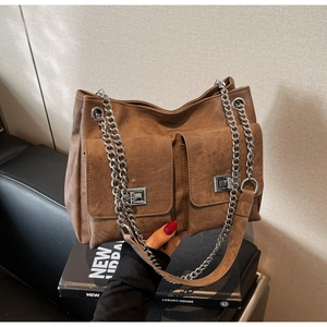 Détail du sac cabas en denim marron avec poches à rabat et bandoulière en chaîne argentée