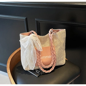 Detail of woven straw tote bag with pink Summer patch and white lace ribbon bow