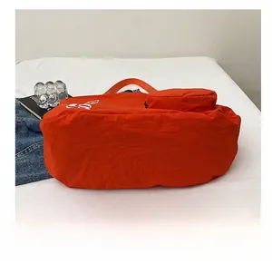 Détail de la base large et résistante d'un grand sac cabas orange en nylon léger