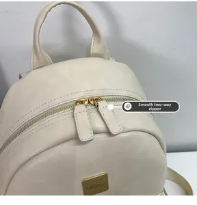 Detail of smooth two-way metal zippers and gold MKBV logo on beige leather backpack
