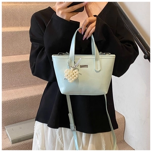 Detail of mint green bucket bag with pearl heart pendant and adjustable strap