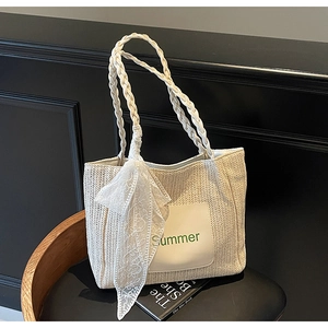 Detail of woven straw tote bag with Summer embroidery and delicate lace scarf accent
