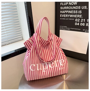 Close-up of pink and white striped canvas tote bag with bold white lettering on the surface