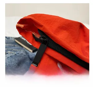 Gros plan de la fermeture éclair noire et du tissu en nylon orange vif du sac fourre-tout
