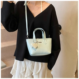 Detail of light blue bucket bag with pearl heart charm and crossbody strap