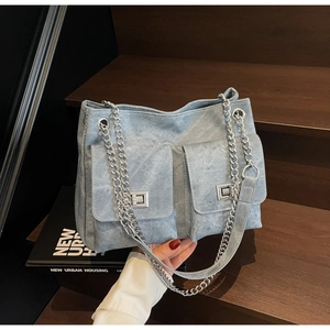 Détail de la texture denim bleu clair et fermoirs rotatifs argentés sur doubles poches
