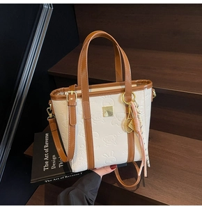 Detail of cream bucket bag with embossed cartoon patterns and tennis racket pendant