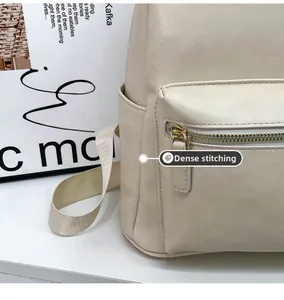Detail of precise stitching on a beige faux leather backpack with gold zipper pocket