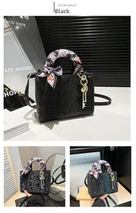 Détail du sac à main noir motif serpent avec foulard décoratif et breloque dorée