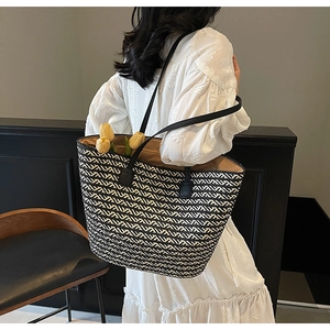 Detail showing the large capacity and black and white woven pattern of the straw tote bag