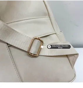 Close-up of adjustable fabric shoulder strap with gold buckle on cream backpack
