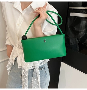 Dettaglio borsa in pelle verde con fibbia a H argentata e perla nera sulla tracolla