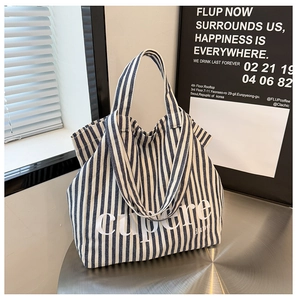Detail of blue and white striped canvas tote bag with large cupere text on a metal table
