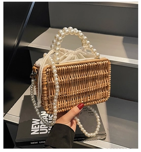 Detail of woven straw bag with pearl handles, drawstring liner, and detachable chain strap