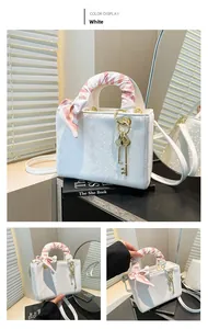 Détail d'un sac blanc texture écailles avec foulard en soie et pendentif clé dorée