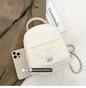 Close-up of cream quilted mini backpack with silver twist lock compared to iPhone 12