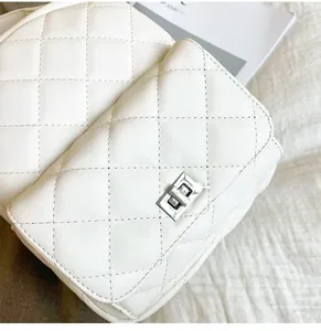 Close-up of quilted white leather texture and silver metallic twist lock on the bag