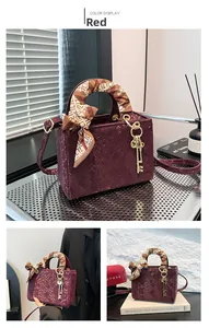 Détail du sac à main bordeaux motif écailles de poisson avec foulard et pendentif doré
