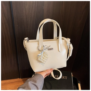 Detail of cream leather bucket bag with silver logo plate and pearl heart pendant charm
