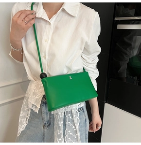 Dettaglio della borsa a tracolla verde brillante con logo H in argento e decorazione a sfera nera