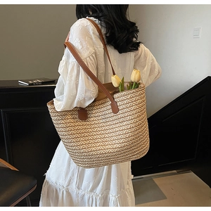 Close-up of a large capacity straw tote bag with brown leather straps and floral accents