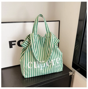 Detail of green and white striped canvas tote bag showing thick texture and letter print