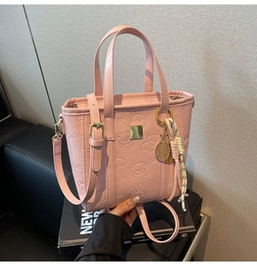 Detailed view of pink embossed bucket bag with cute cartoon patterns and tennis racket charm
