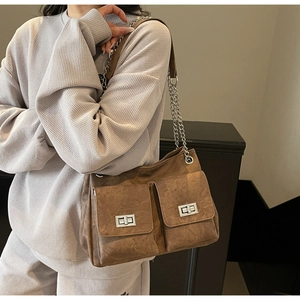 Détail d'un sac cabas en daim marron avec doubles poches avant et fermoirs rotatifs argentés