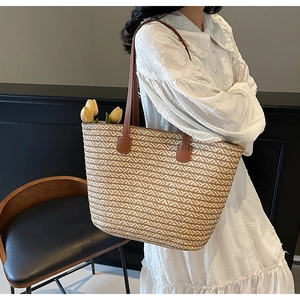 Detail of V-shaped woven straw tote bag with brown leather straps and tulip decor