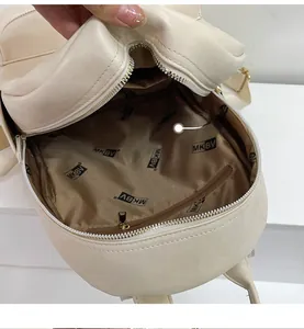 Detail view of the cream white backpack interior with brown logo lining and zip pocket