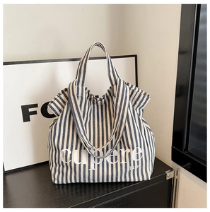 Detail shot of a large striped canvas tote bag with white cupere letter printing