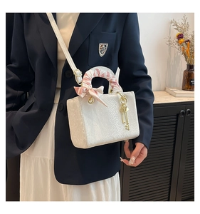 Détail d'un sac à main blanc à texture écailles avec foulard en soie sur la poignée