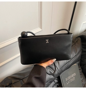 Dettaglio del logo H in metallo argentato su una borsa a tracolla in pelle nera minimal